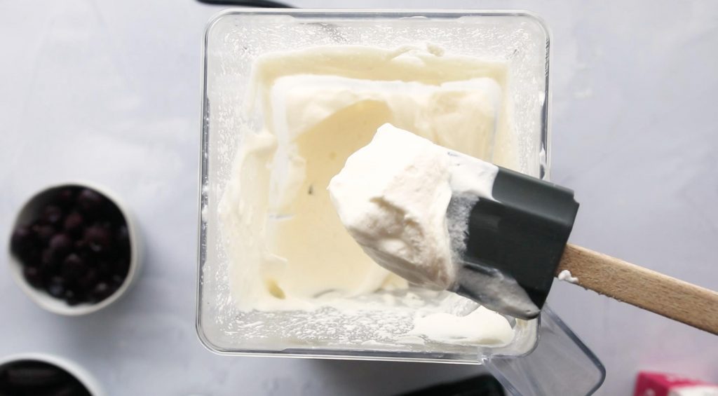 spatula with whipped cream on it over a blender full of whipped cream