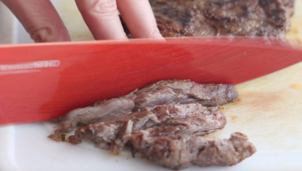 slicing steak with a red knife