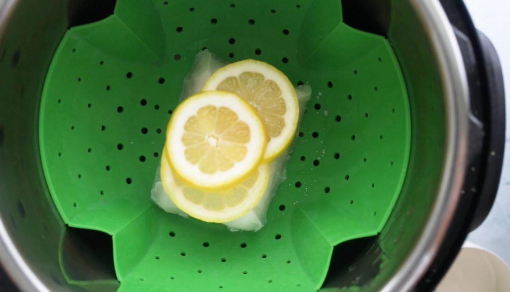 cod with lemon on top on a steamer basket