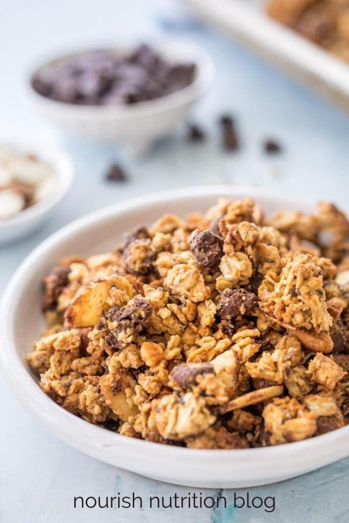 close up of protein granola in a bowl with ingredients in the back
