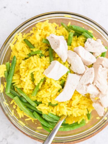 close up of chicken and yellow rice in a glass bowl