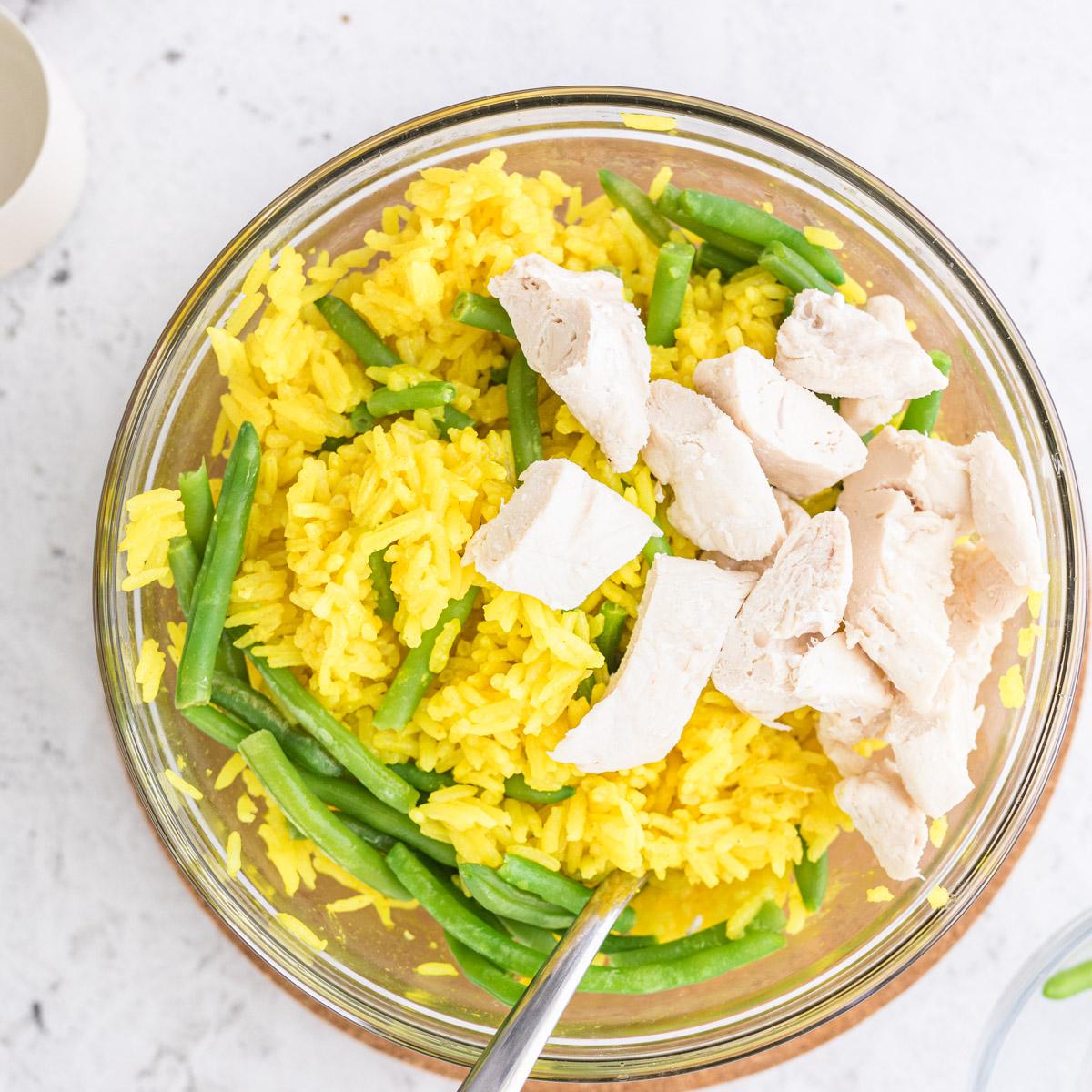 close up of chicken and yellow rice in a glass bowl