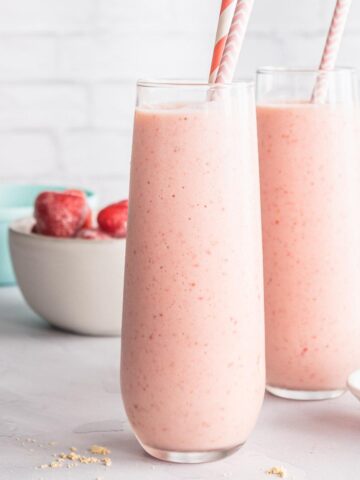 strawberry banana peanut butter smoothies on a table with ingredients in back