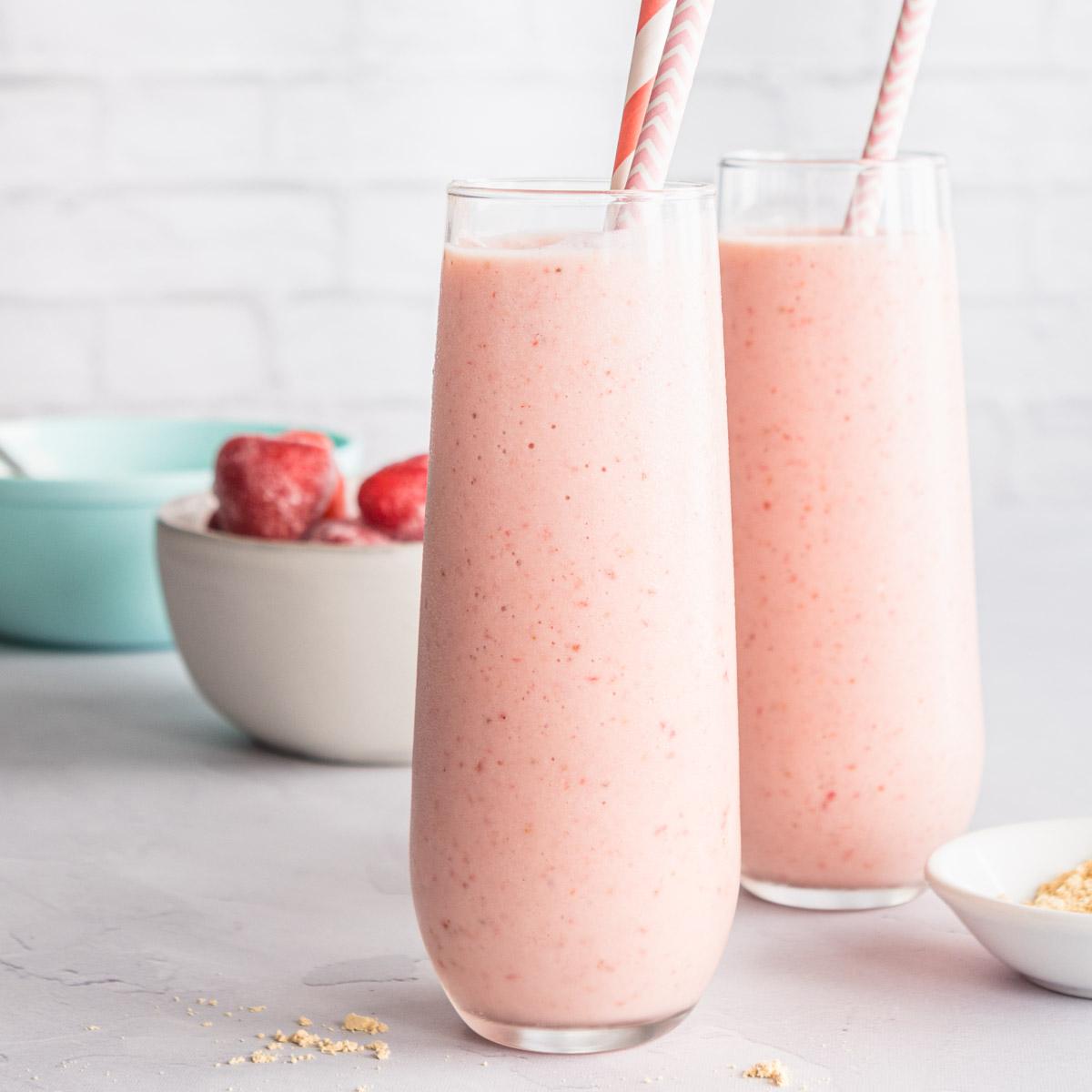 strawberry banana peanut butter smoothies on a table with ingredients in back