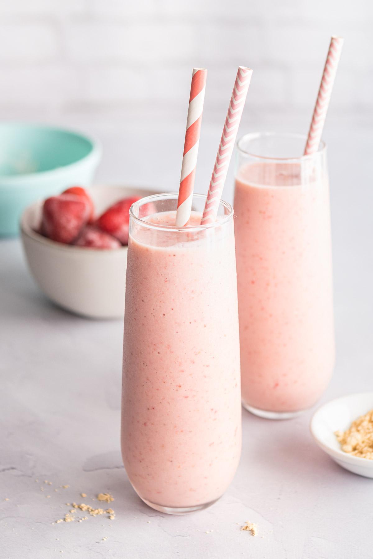 two glasses of strawberry banana smoothie with two straws in each