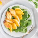light blue plate with spinach, orange slices, and roasted pears on it
