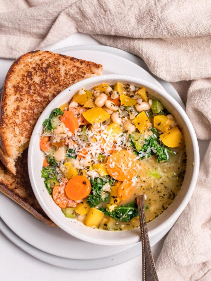close up of delicata squash soup in a white bowl with grilled cheese