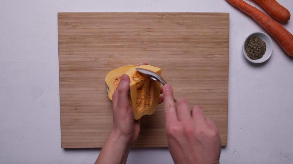 hands scooping seeds out of delicata squash