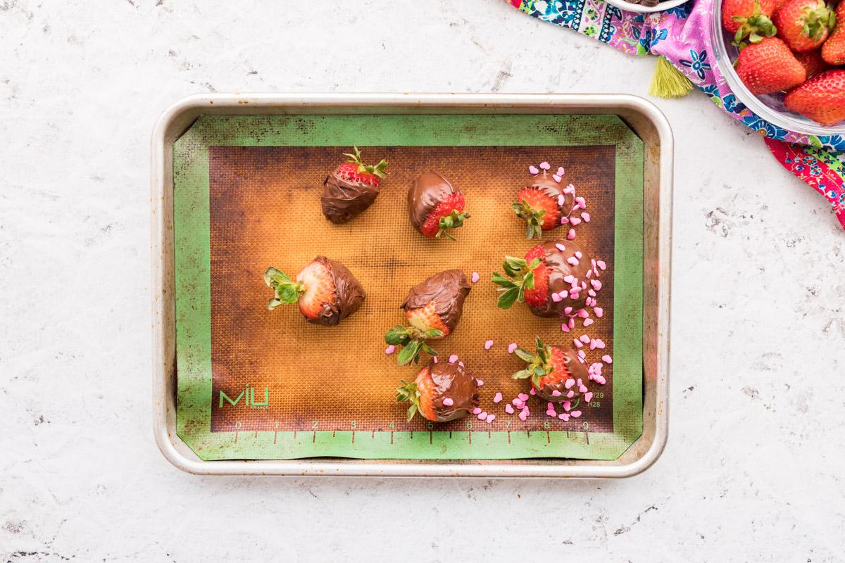 8 chocolate covered strawberries on a cookie sheet