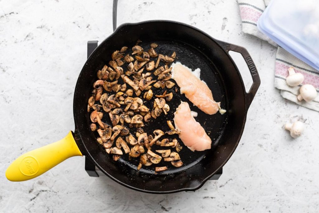 cooked mushrooms and chicken in a cast iron skillet