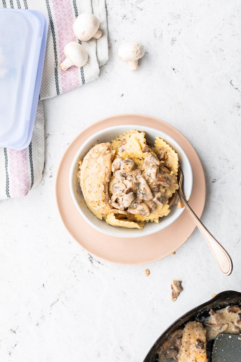 ravioli with mushrooms and chicken in a white bowl with mushrooms around it