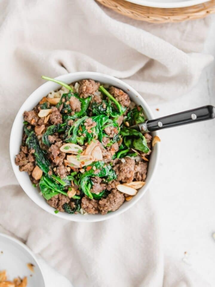 close up of beef, sauteed spinach, garlic, and red pepper flakes in a bowl