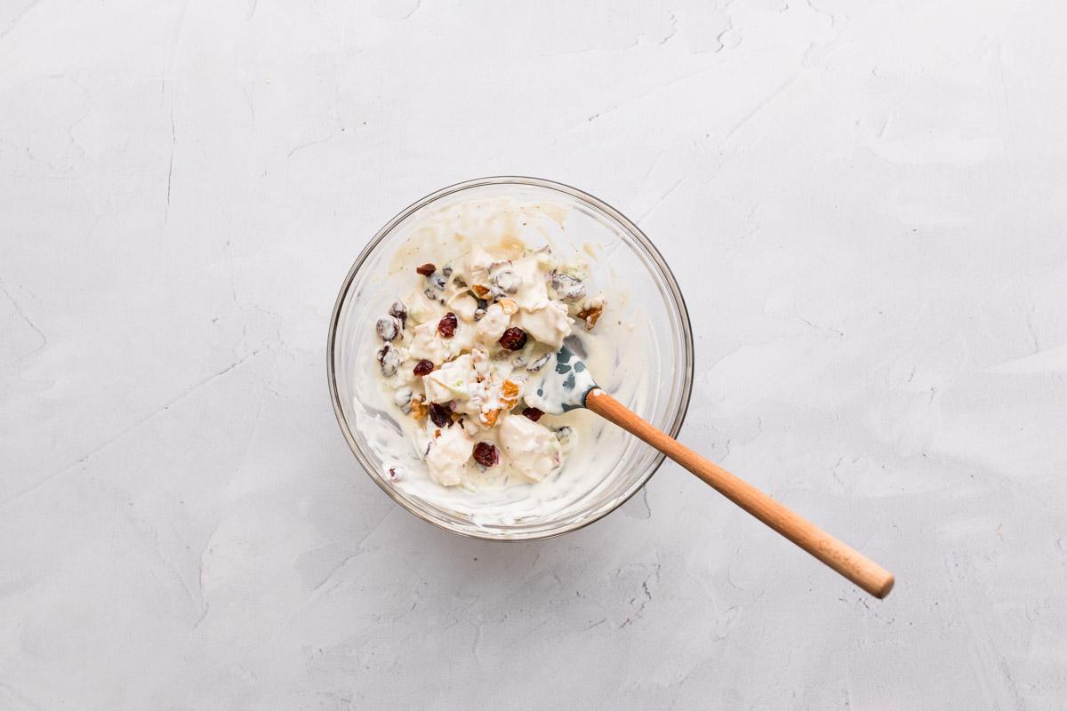 cranberry, walnut chicken salad in a glass bowl with rubber spatula in it