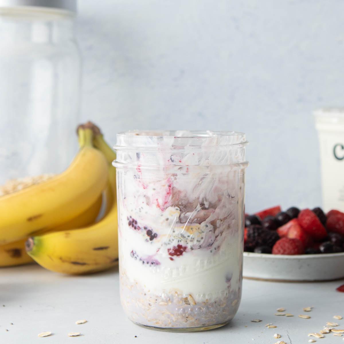 glass jar with oats, chia seeds, and frozen berries in it