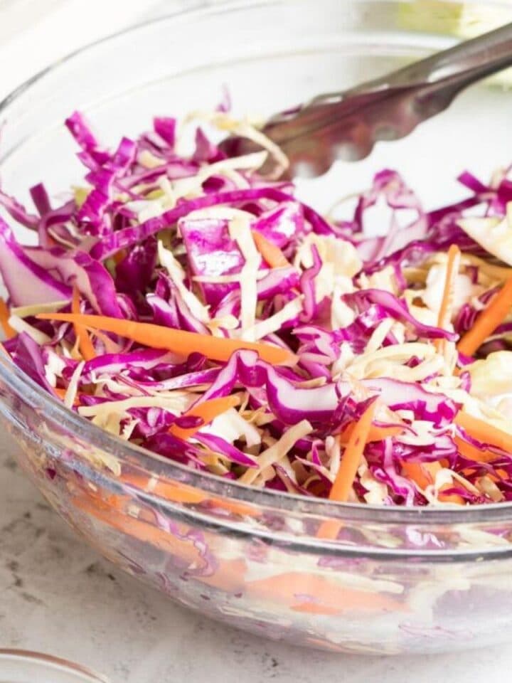 glass bowl of red and green cabbage and shredded carrots