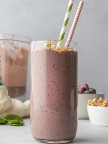 smoothie with granola and 2 paper straws in a tall glass