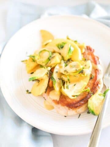 pork chop with apples and brussles sprouts on plate