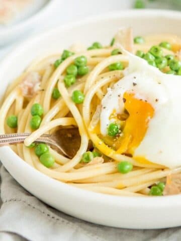 pasta with peas, prosciutto, and a poached egg in a bowl