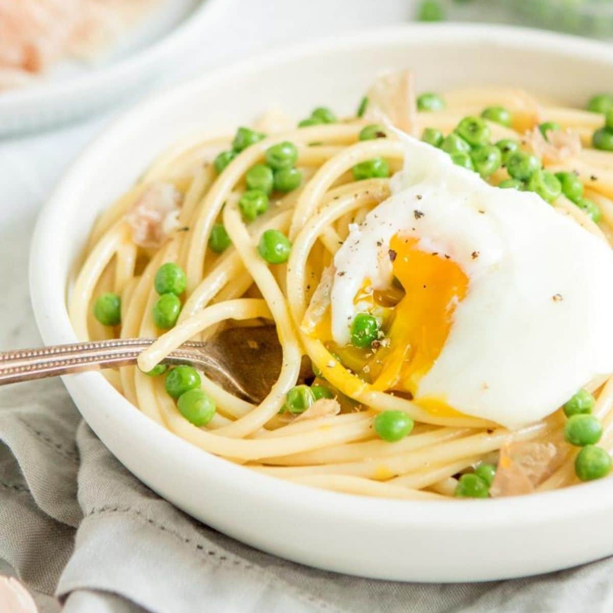 pasta with peas, prosciutto, and a poached egg in a bowl