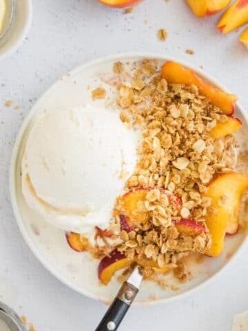 peach crisp with vanilla ice cream on a plate