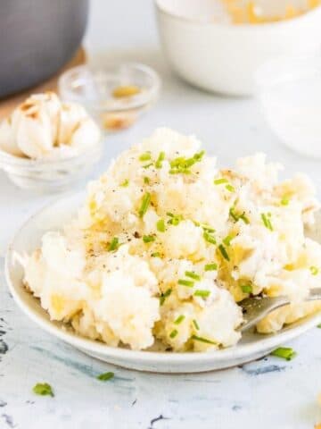 cheesy mashed potatoes on a plate with chives on top