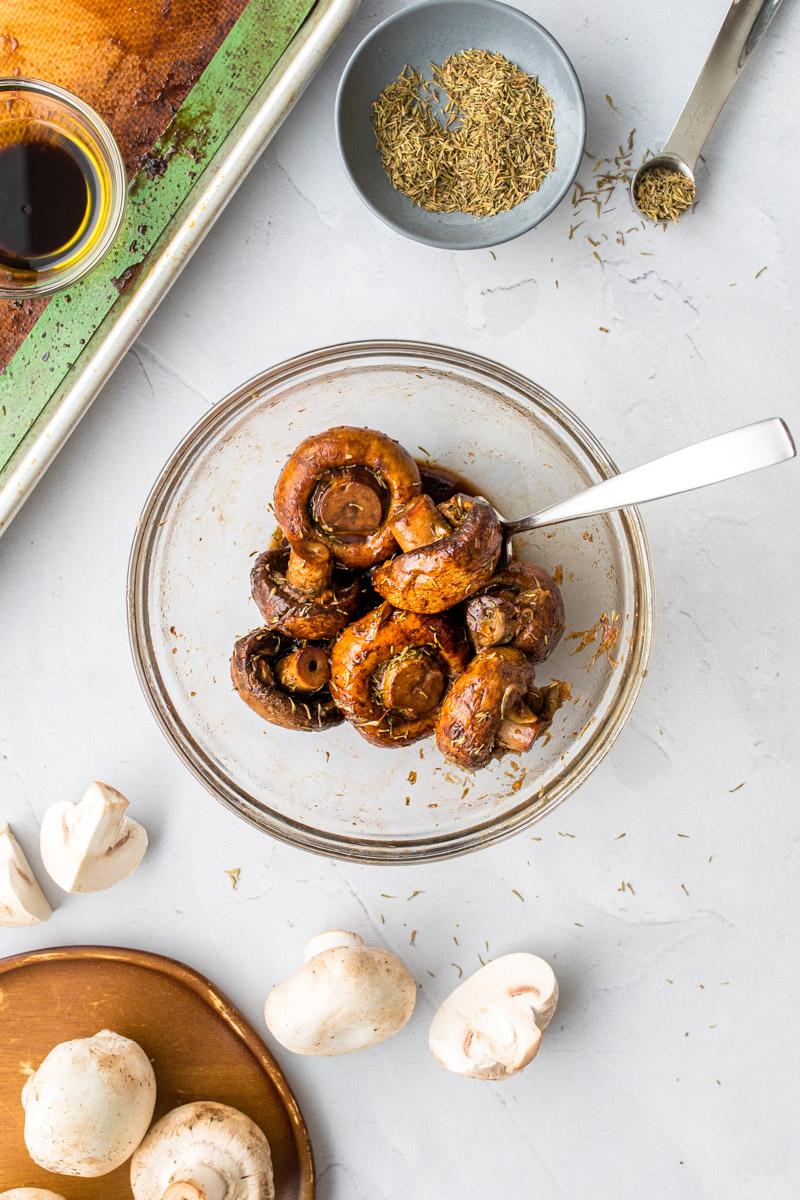 bowl of balsamic mushrooms on a table with ingredients around it