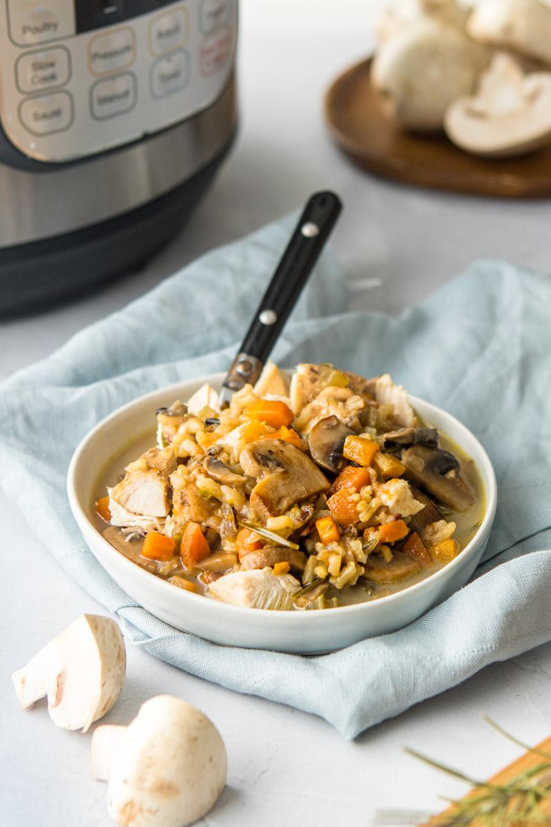 wild rice and mushroom soup in a bowl with ingredients around it