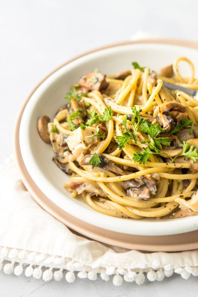 chicken bacon mushroom pasta on a white plate with parsley