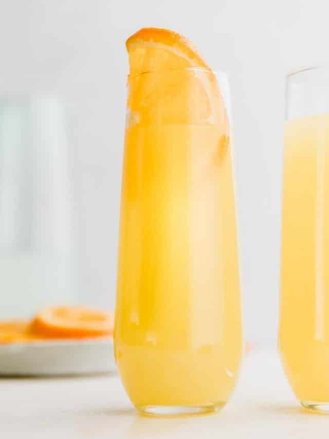 close up of a mimosa in a tall glass with orange wedge in it