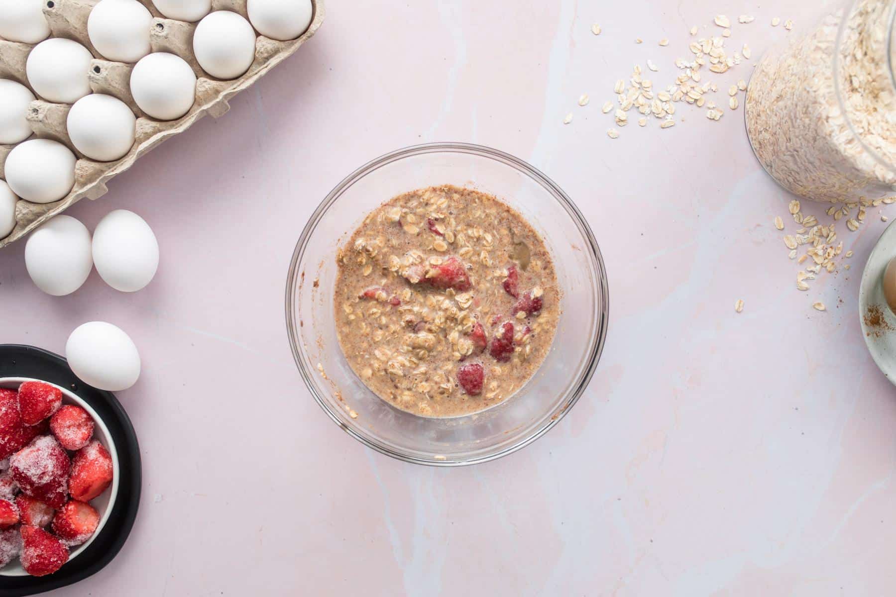 uncooked oatmeal batter with strawberries in a glass bowl