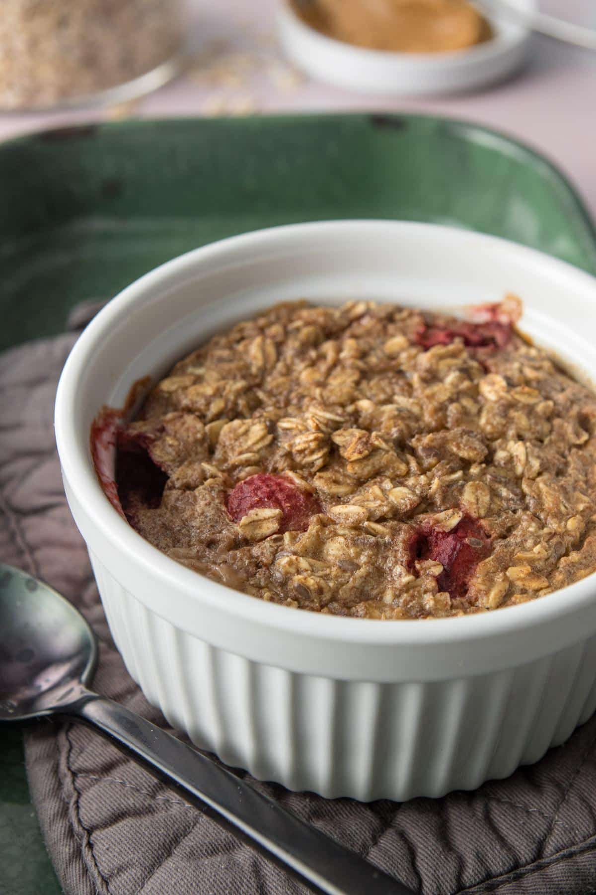 oatmeal with strawberries in white ramekin over grey hot pad