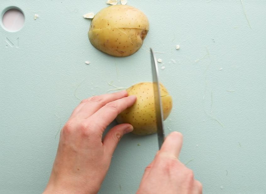 cutting yukon gold potato half on a green cutting board