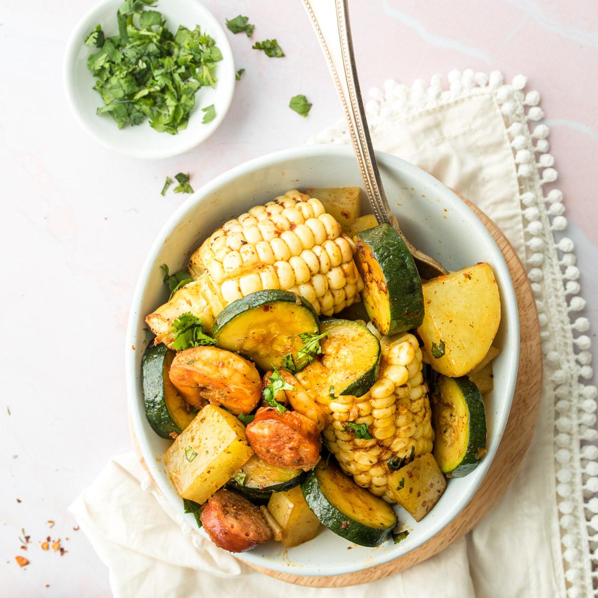 corn, zucchini, potatoes, and sausage in a bowl