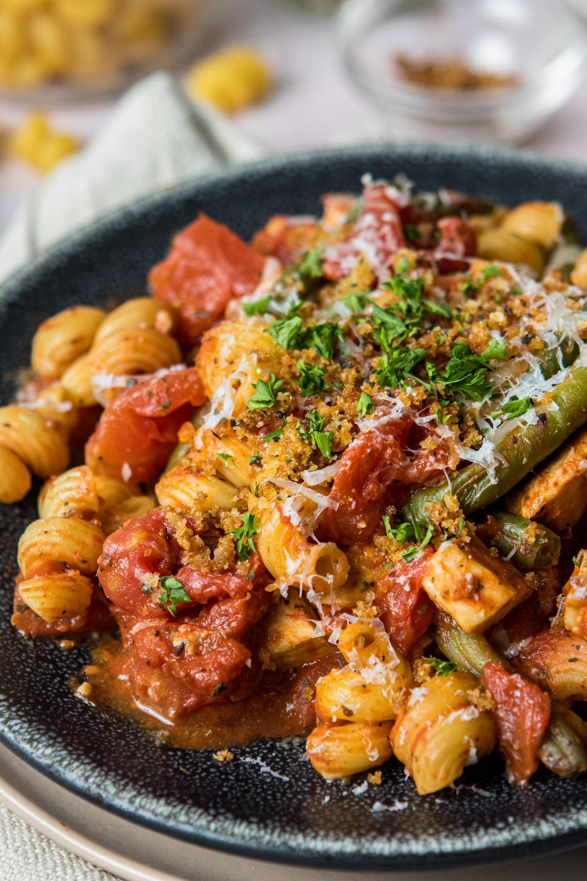 close up of pasta with pasta sauce on a black plate