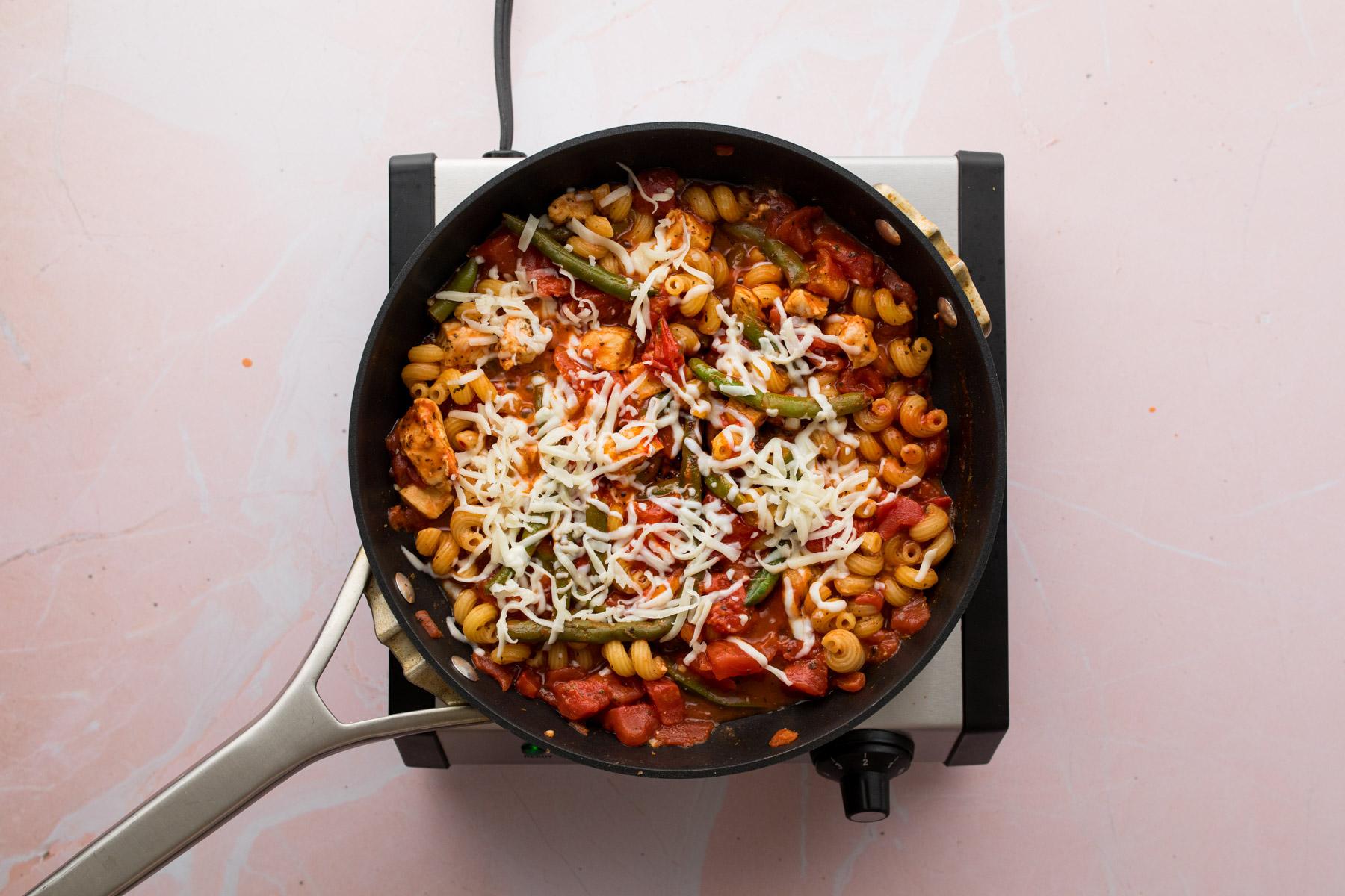 chicken parmesan pasta with cheese in a skillet
