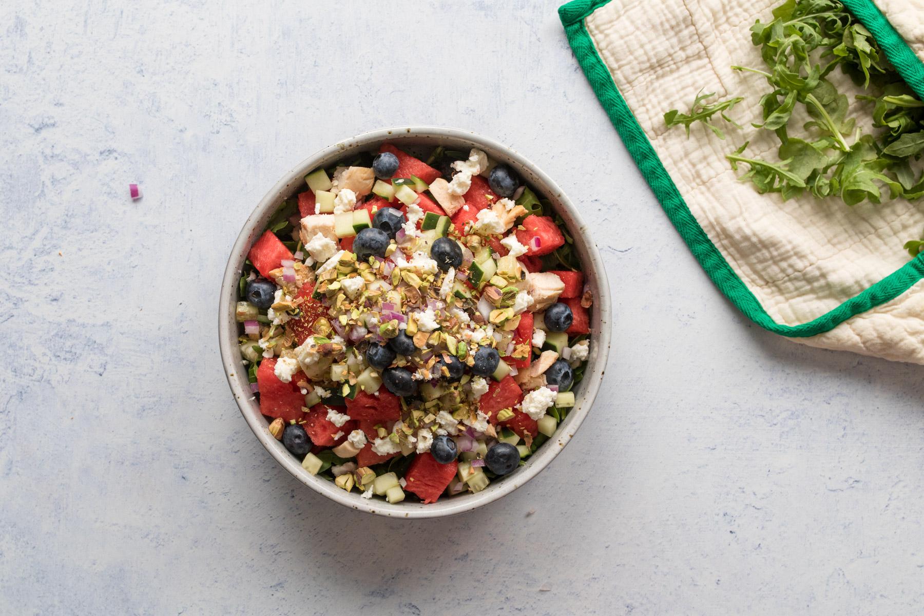 bowl of watermelon, feta, blueberries and other salad ingredients