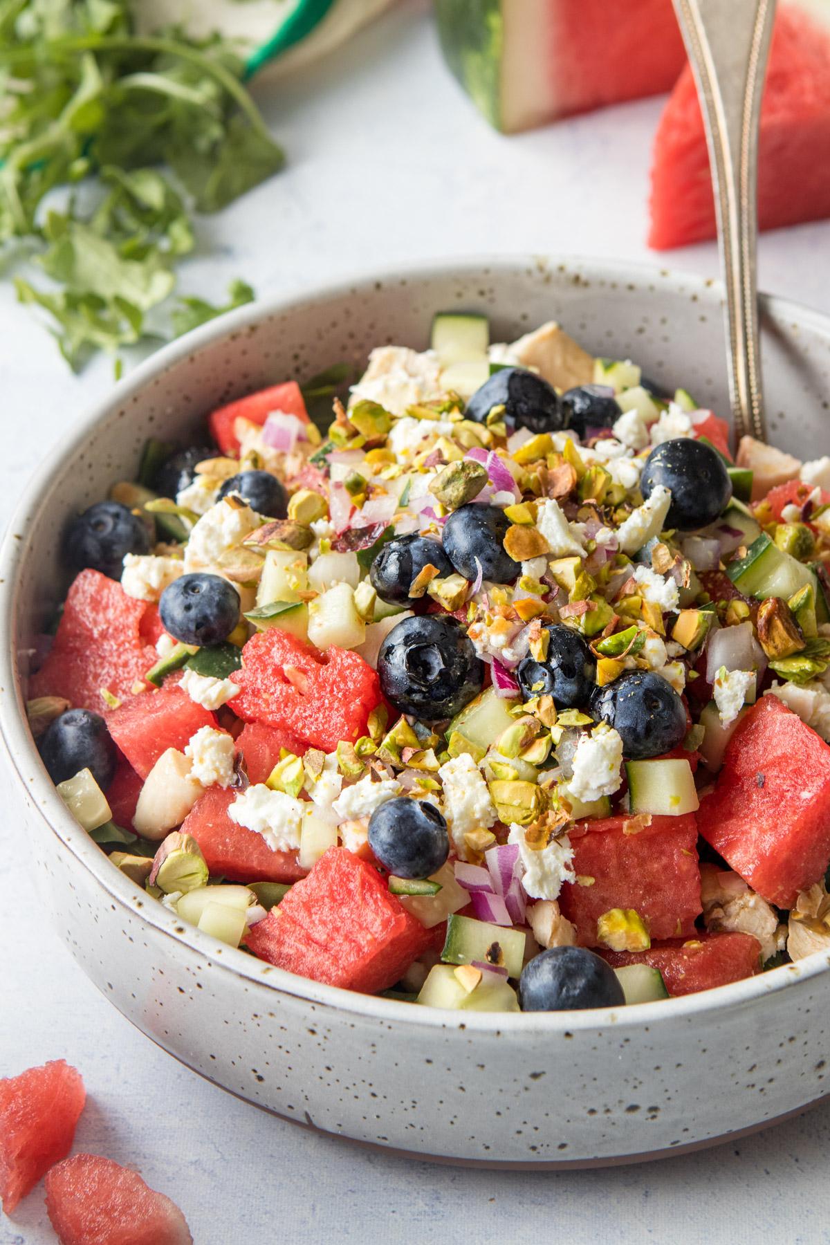 close up of watermelon, feta cheese, and blueberries in a large bowl