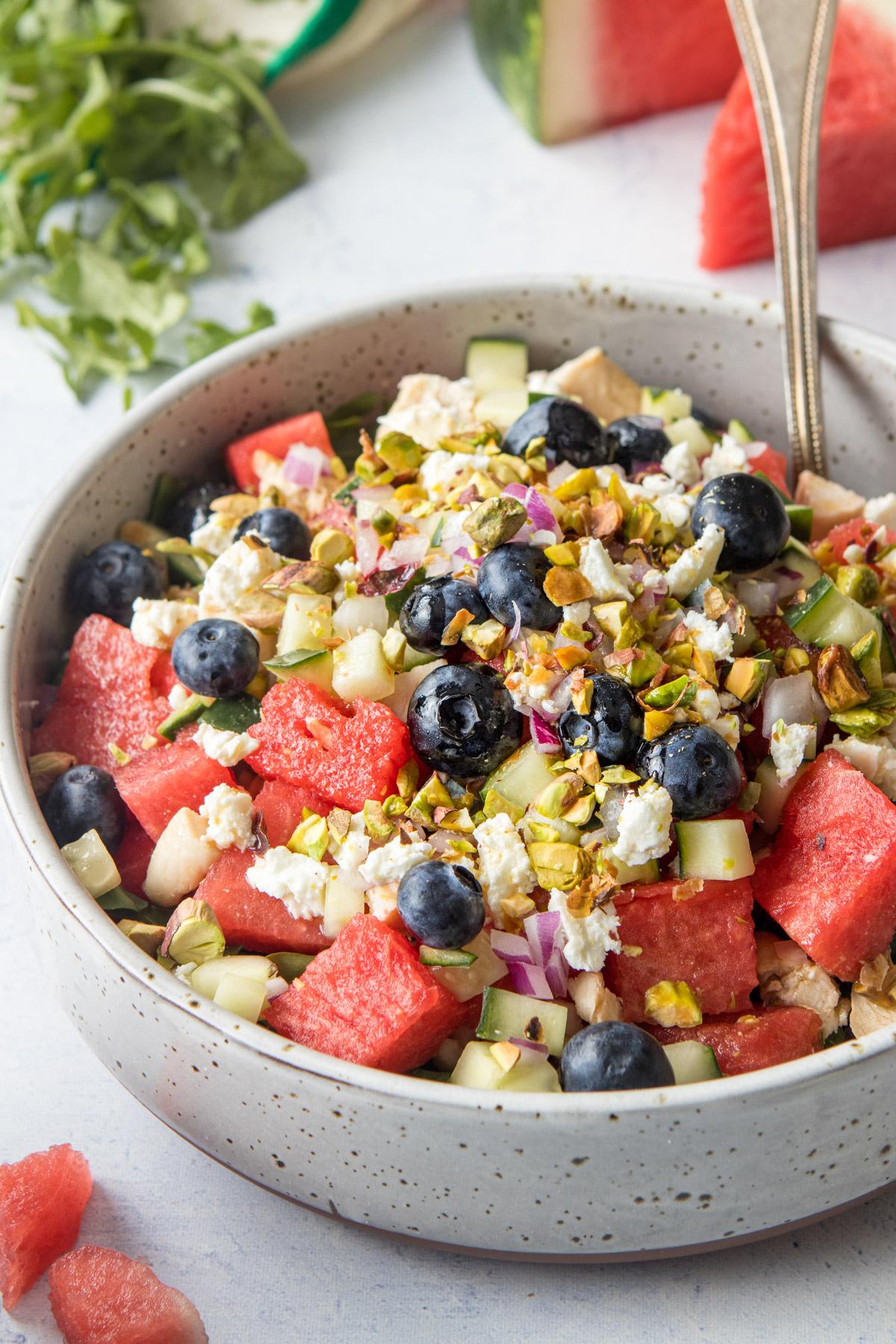 close up of watermelon, feta cheese, and blueberries in a large bowl