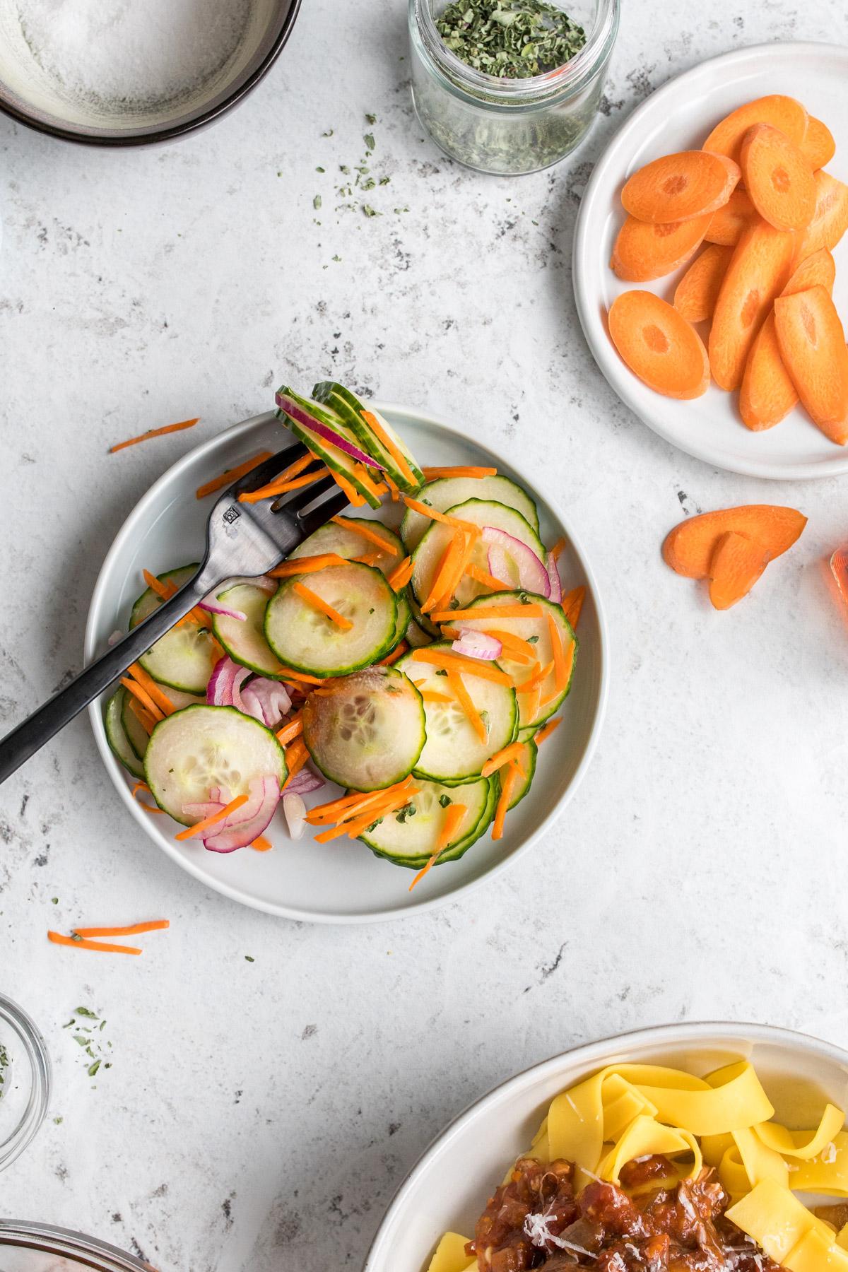 sliced cucumber salad on a plate with black fork
