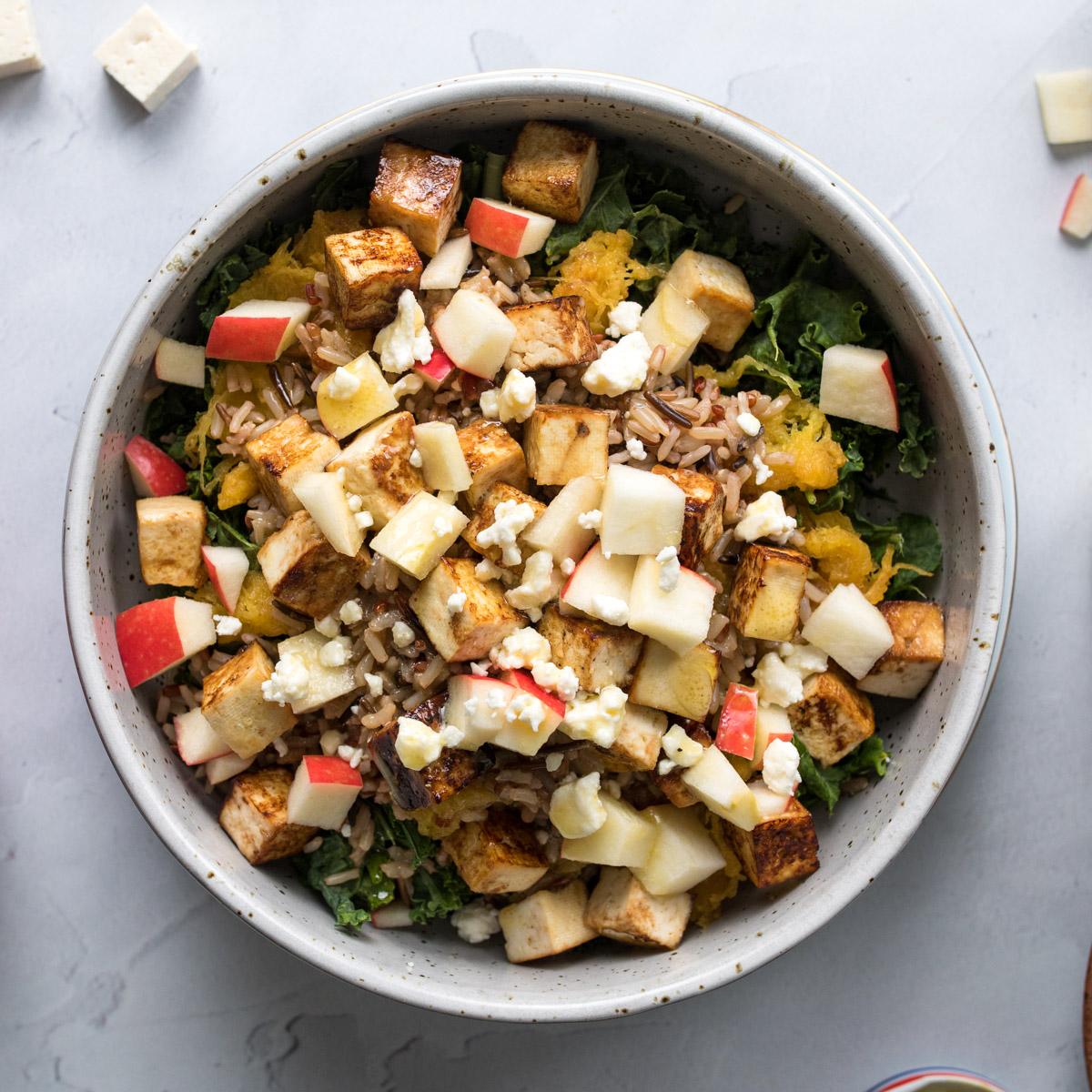 square image of a grain bowl with apples and tofu