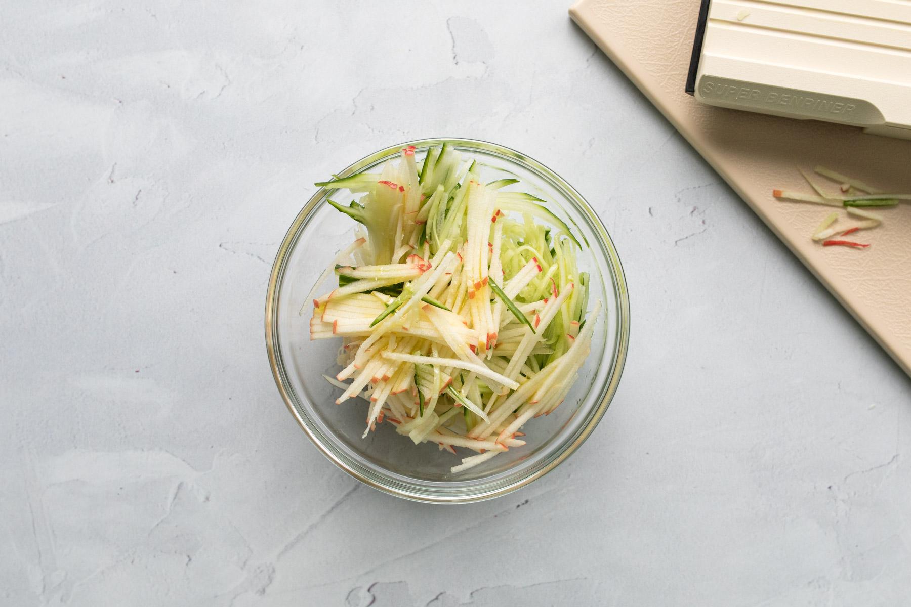 thinly sliced apples and cucumbers in a bowl