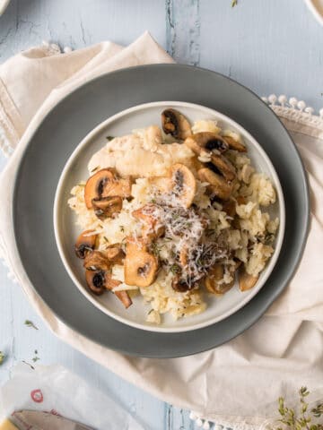 mushrooms and chicken over rice on a white and grey plate