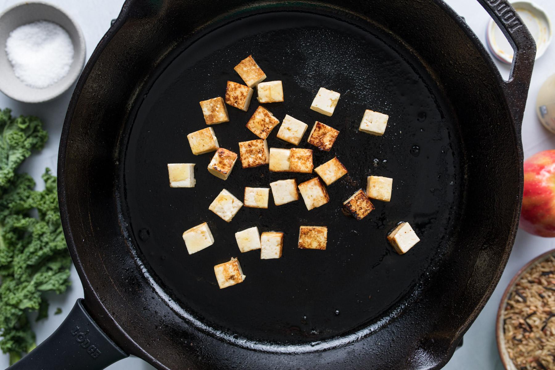 cubed tofu frying in a skillet