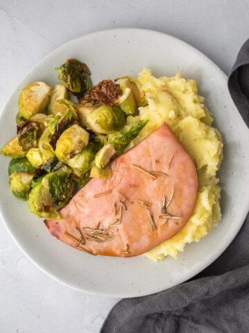 square image of ham and veggies on the side
