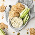 artichoke dip with crackers and veggies on a plate