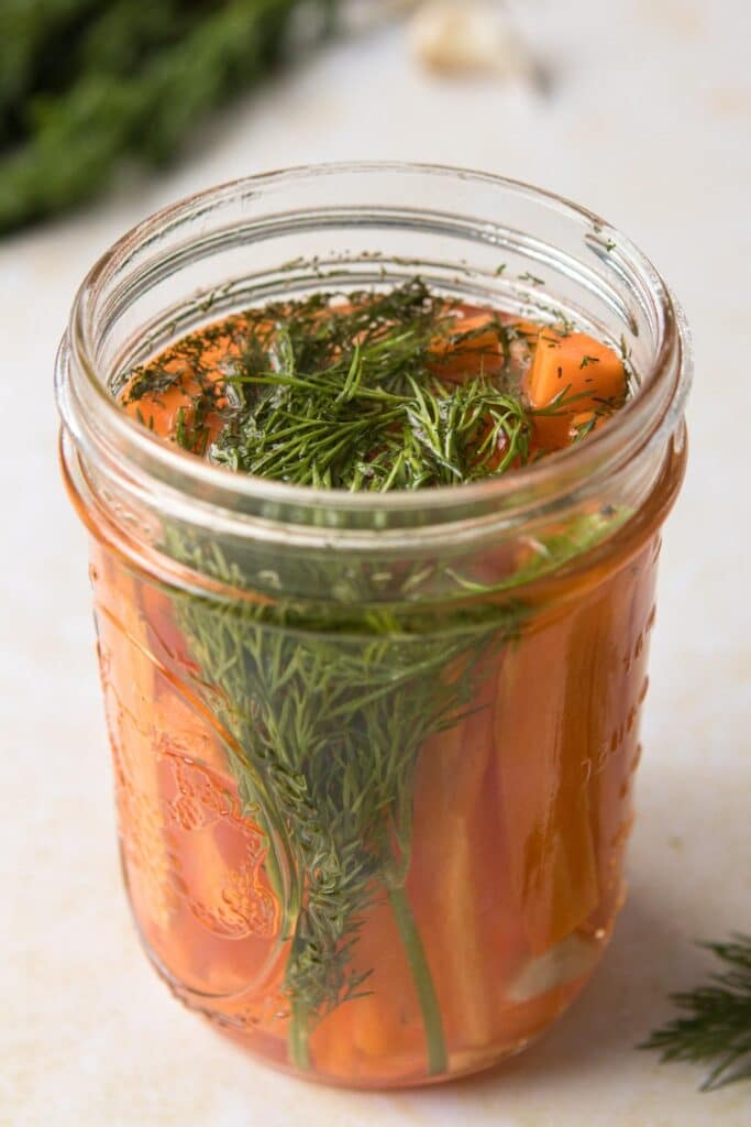 glass jar with fresh dill and carrots in it