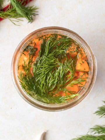 dill draped over sliced carrots in jar