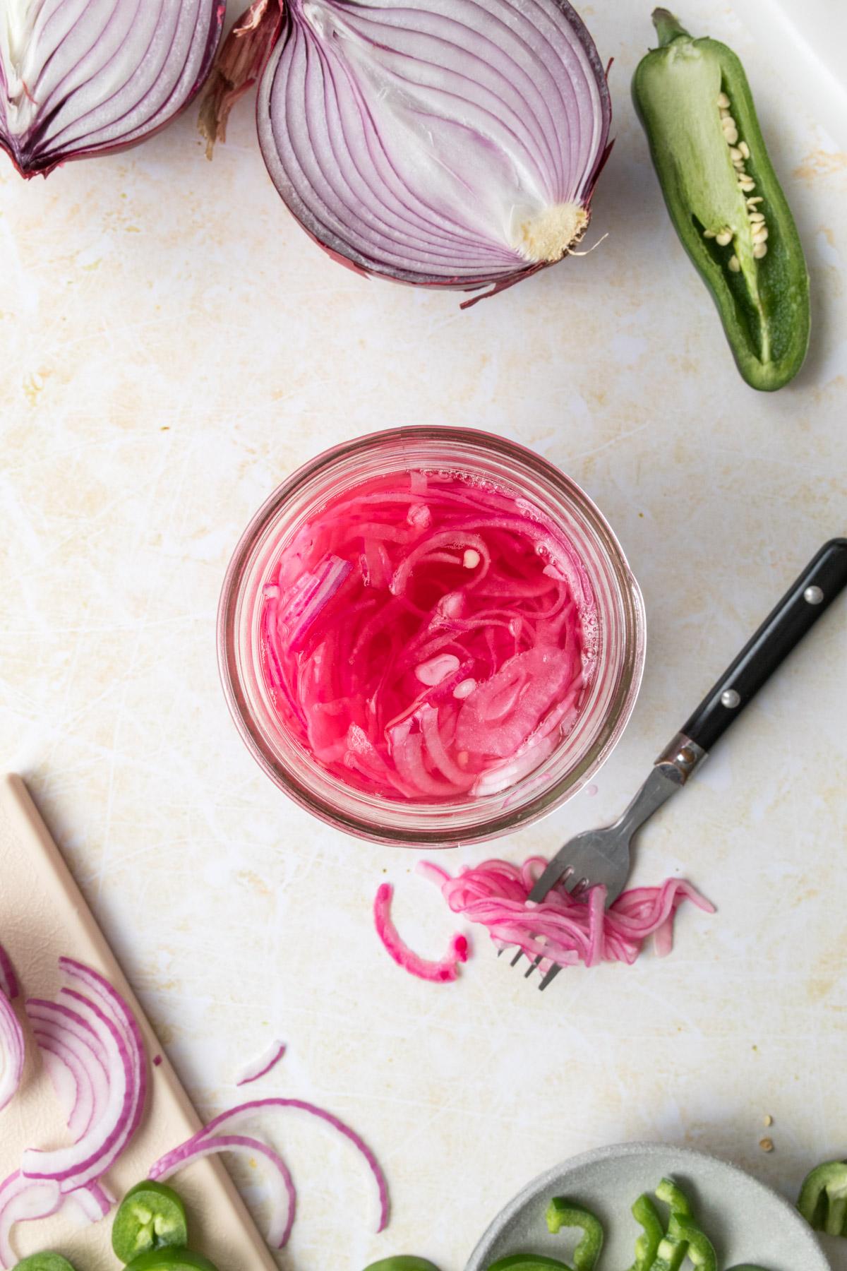 fork with pickled onions and jar of pickled onions