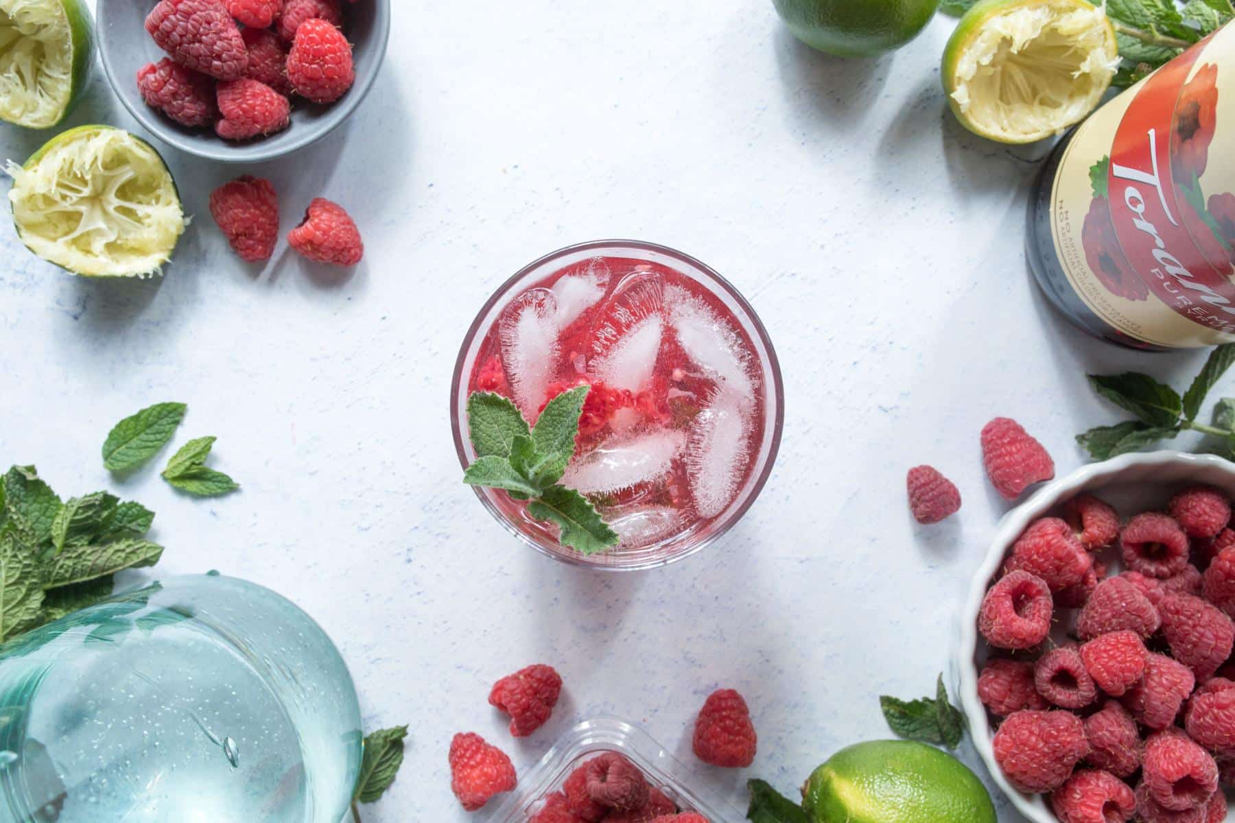 raspberry drink with ice surrounded by ingredients