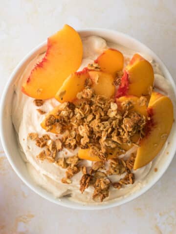 close up of yogurt with granola and yellow peach slices